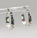 A pair of polished Sterling Silver small hoop earrings featuring an embossed or engraved pattern of crescent moons and stars, with small multi-color CZ accents.