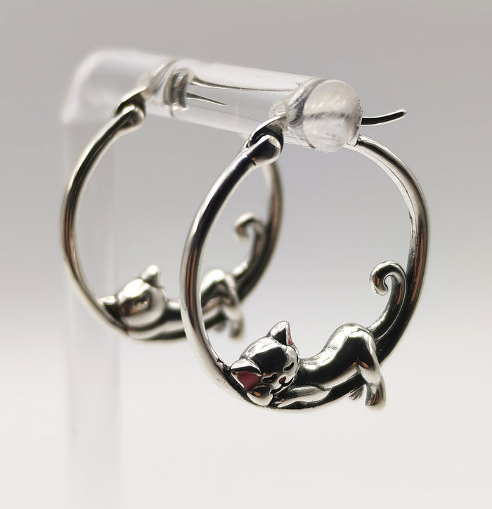 Side-angle photo showing the curved hoop and detailed curled-tail sleeping cat charm in sterling silver.
