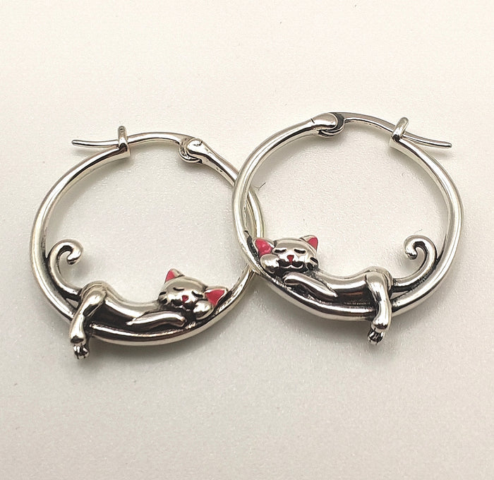 Macro shot highlighting the fine detailing of the sterling silver sleeping cat on the hoop earring.