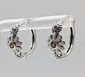 Sterling silver daisy hoop earrings with amber zirconia stones on display stand