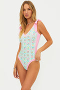 Woman wearing a floral one-piece swimsuit with pink accents on a white background
