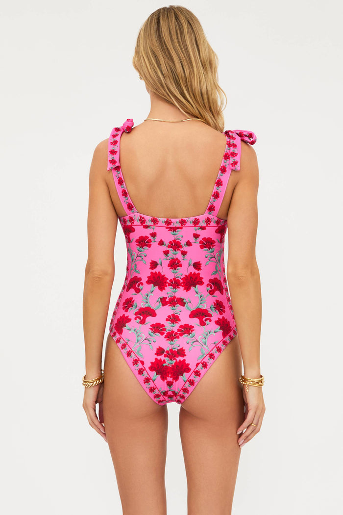 Woman wearing a pink floral one-piece swimsuit on a white background