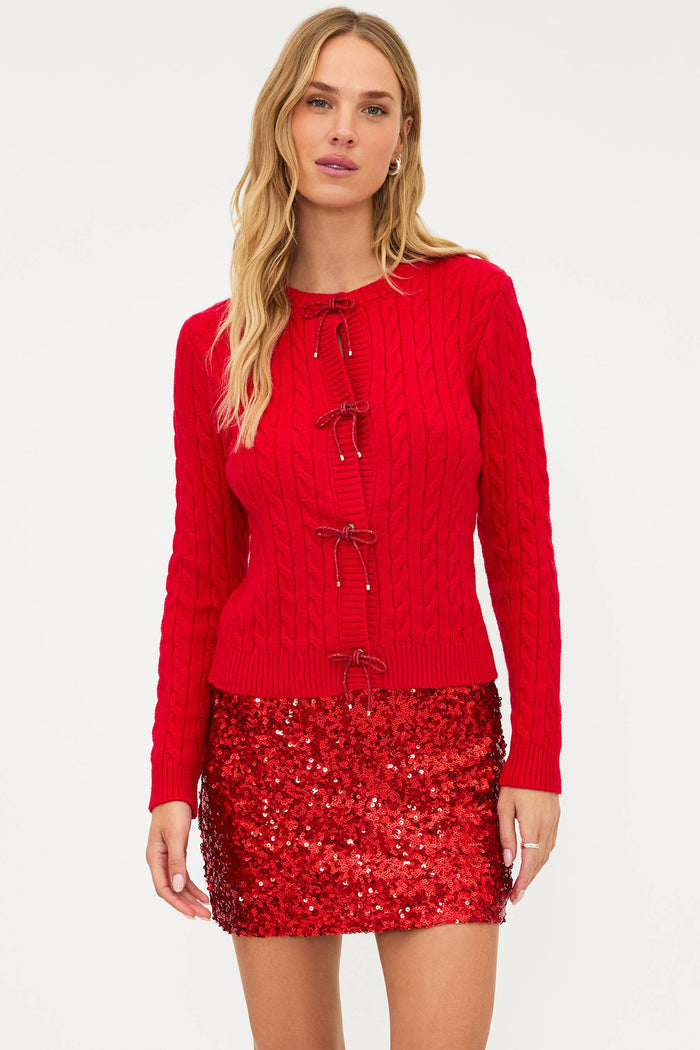 Woman wearing a red knitted top and sequin skirt on a white background