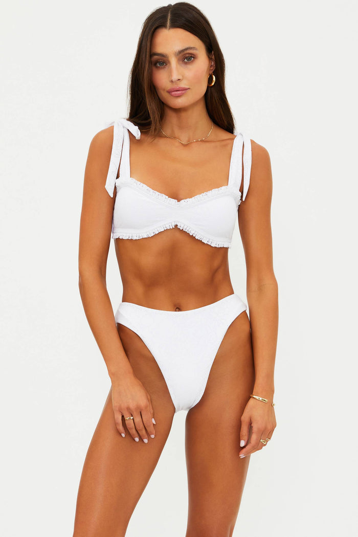 Woman wearing a white high cut swim bottoms with pointelle knit fabric.