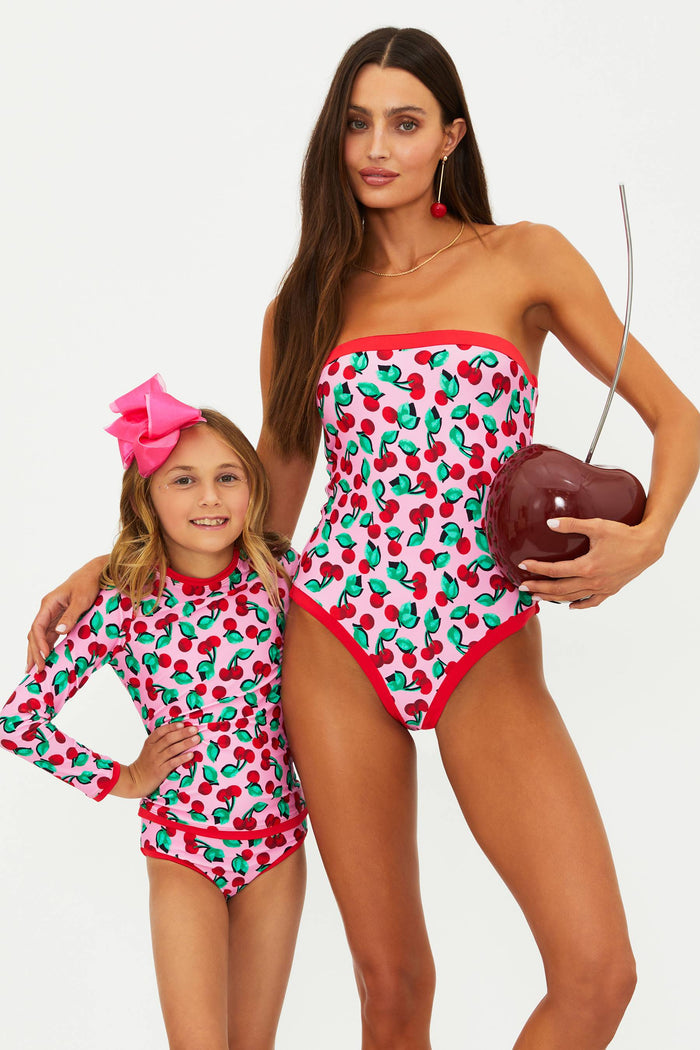 Woman and child wearing a strapless one piece with pink and red cherries.