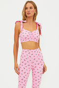 Woman wearing a pink cherry sports bra on a white background.