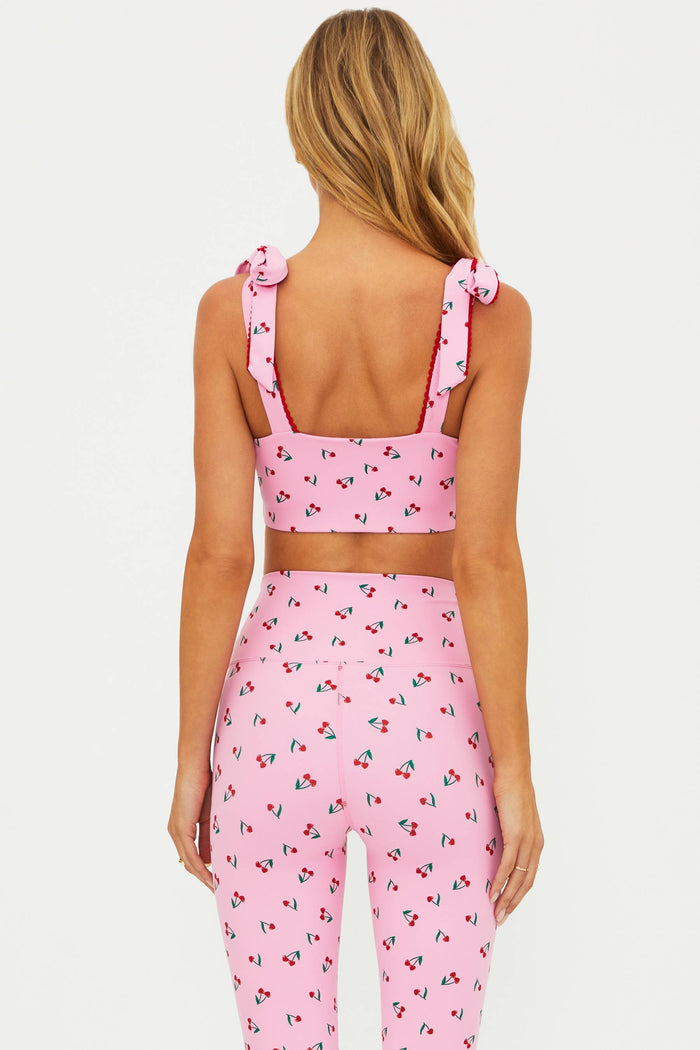 Woman wearing a pink cherry sports bra on a white background.