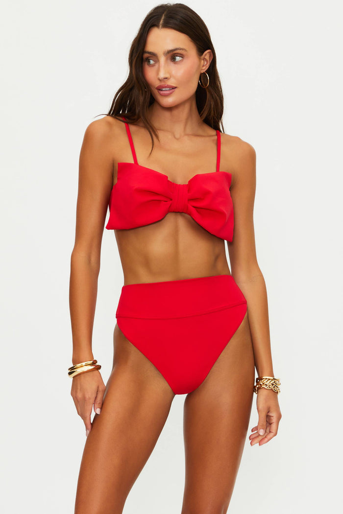 Woman wearing a red bikini with a large bow on a white background