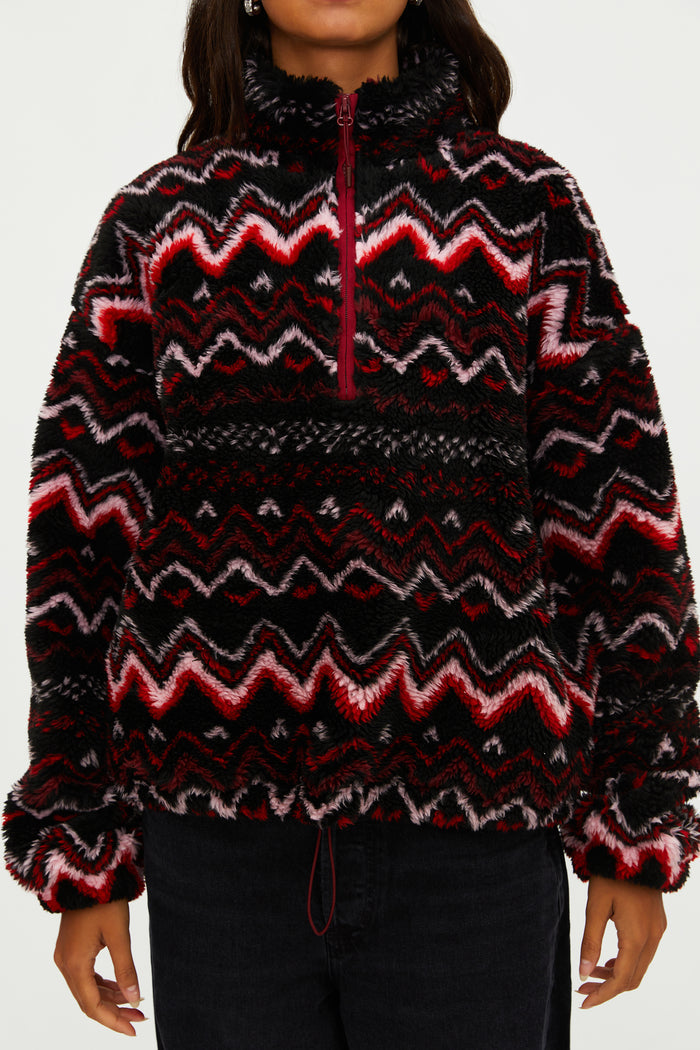 Person wearing a patterned sweater with red and black design