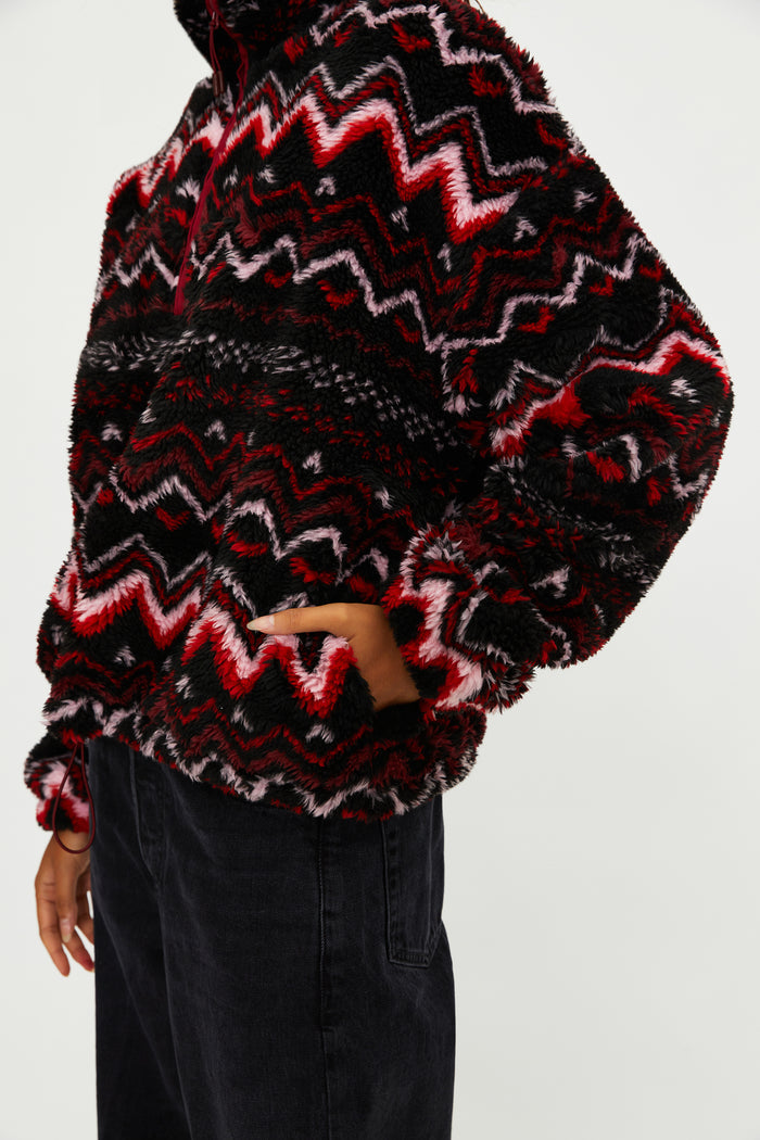 Person wearing a black and red patterned sweater on a white background
