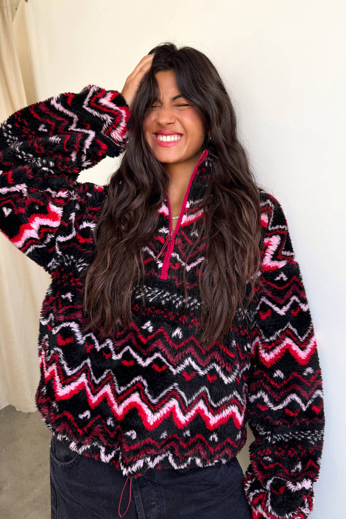 Woman wearing a colorful patterned sweater against a plain background