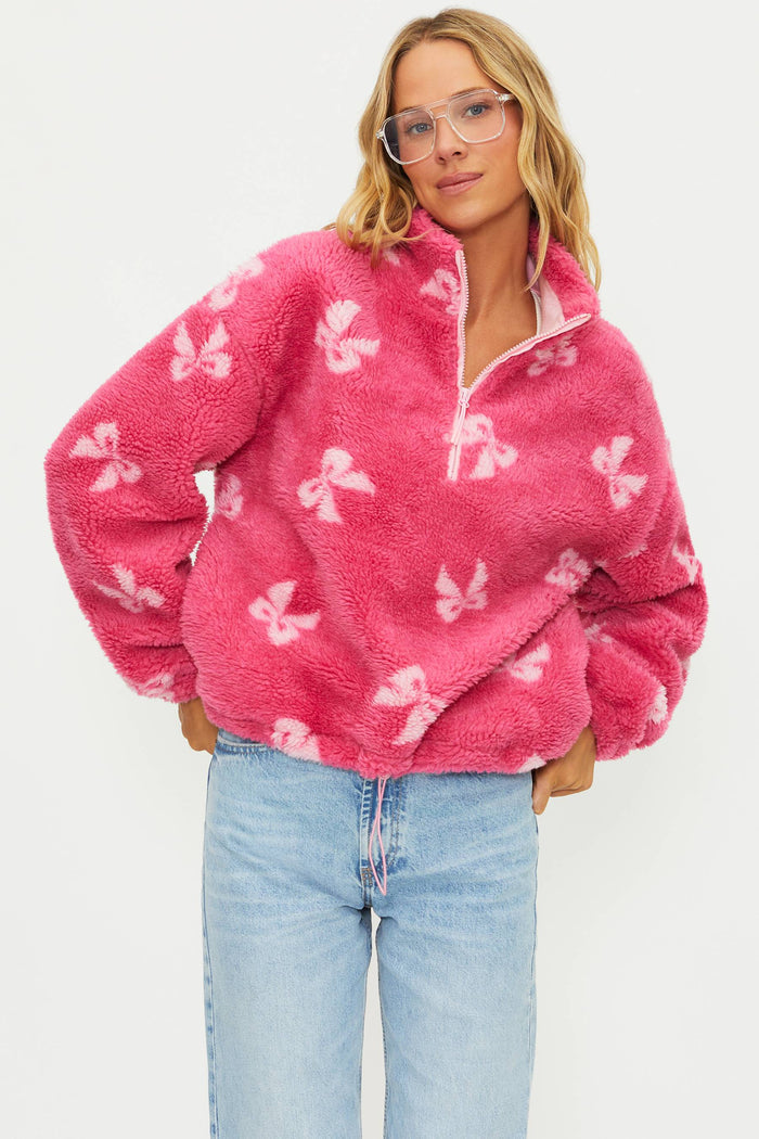 Person wearing a pink fleece pullover with butterfly patterns on a white background