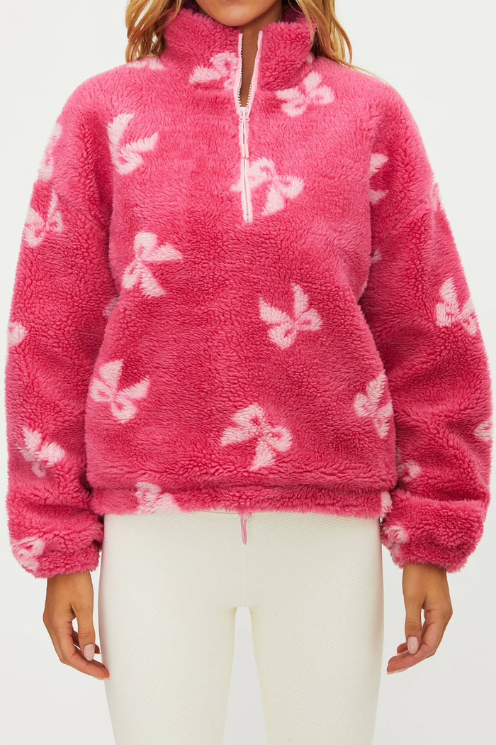 Pink fleece pullover with butterfly patterns worn by a person on a white background