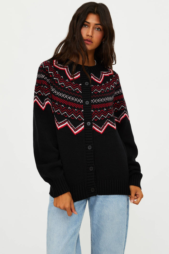 Person wearing a black cardigan with colorful pattern on a white background