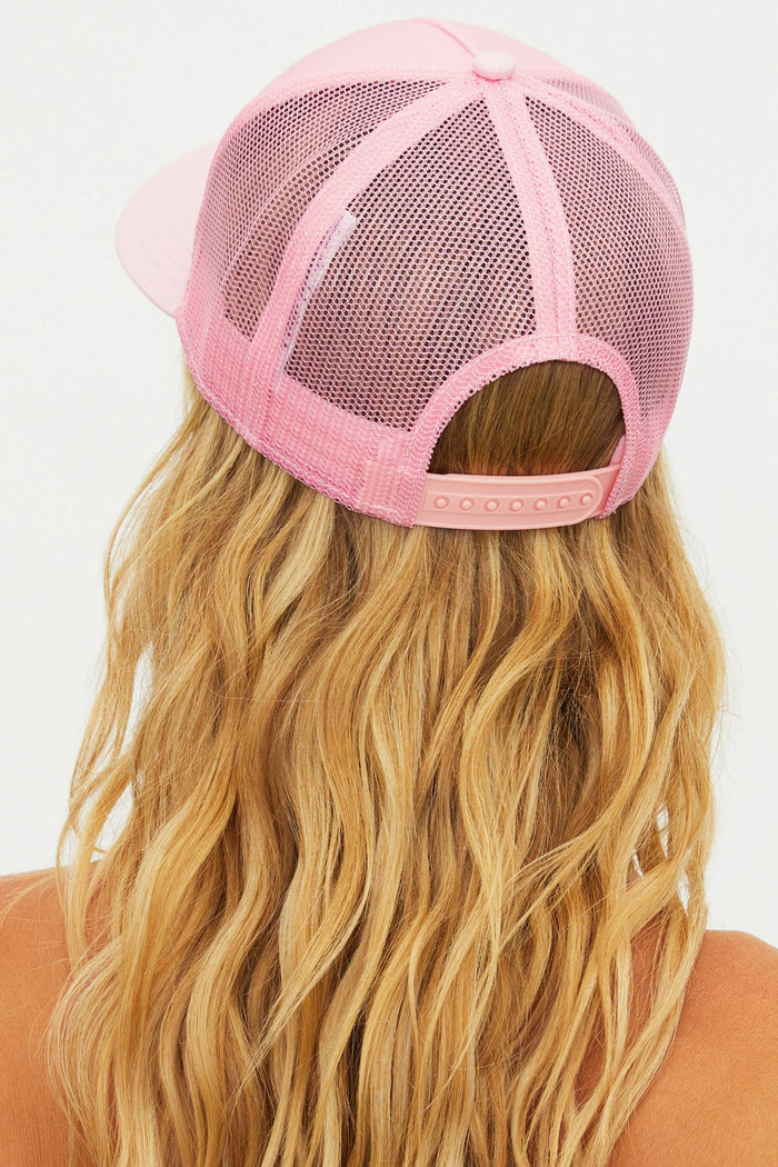 Pink mesh cap worn by a person with long blonde hair on a white background
