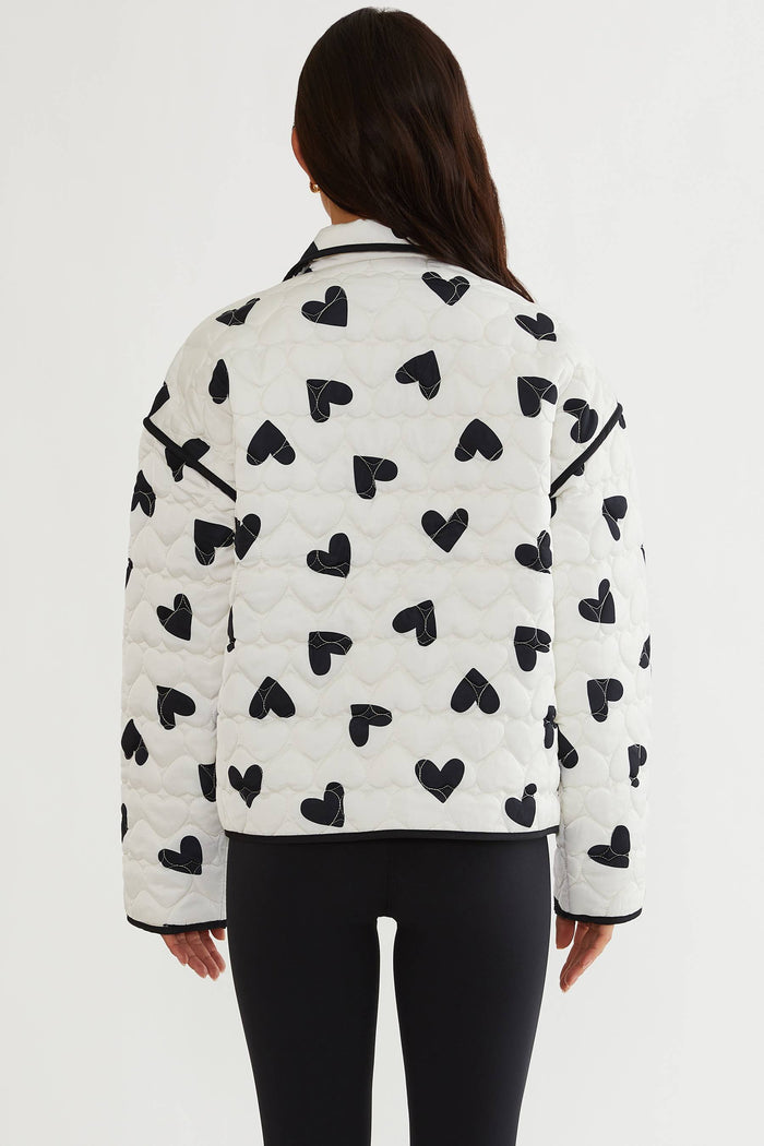 Person wearing a white jacket with black heart patterns on a white background