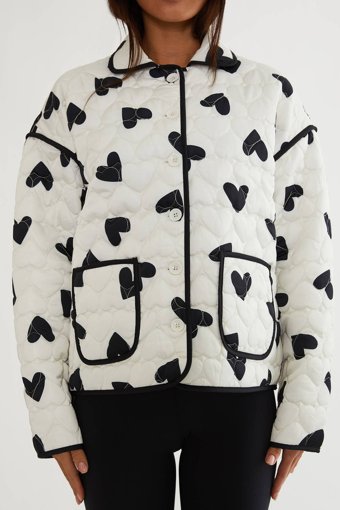 White puffer jacket with black heart patterns on a white background