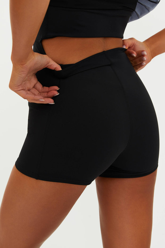 Person wearing black athletic shorts on a plain background