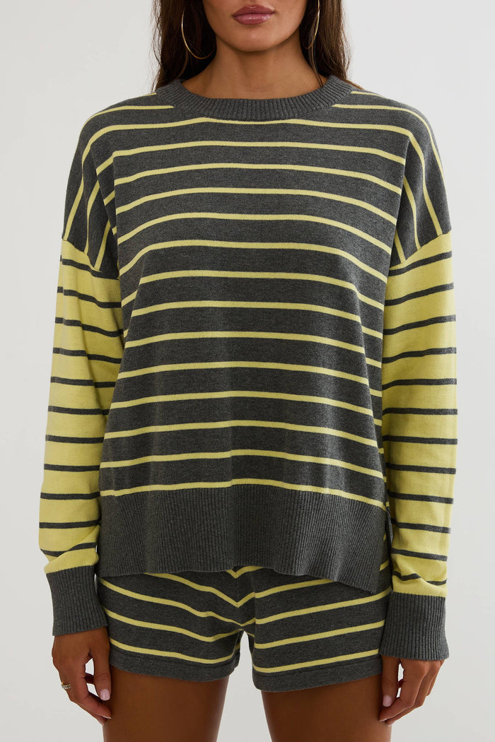 A woman wearing a dark gray and yellow striped knit sweater with matching striped shorts, shown from the mouth down against a plain light background.