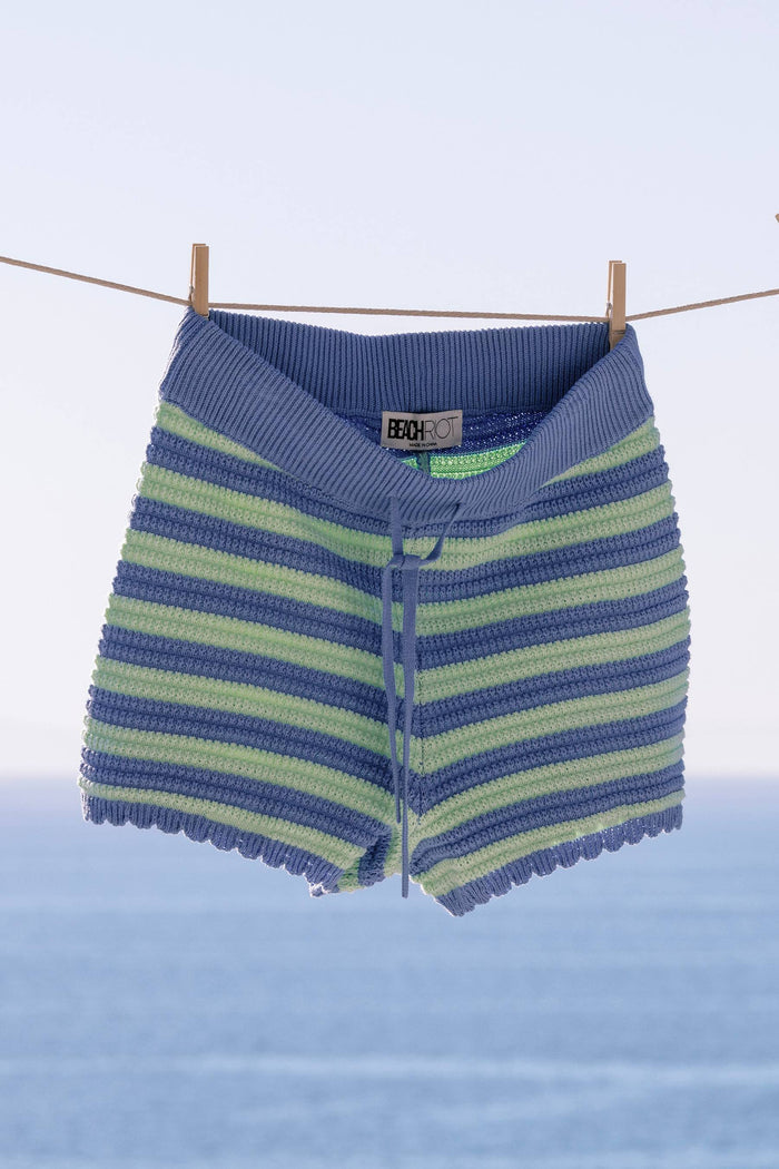 Blue and green striped baby romper hanging on a clothesline against a blue background