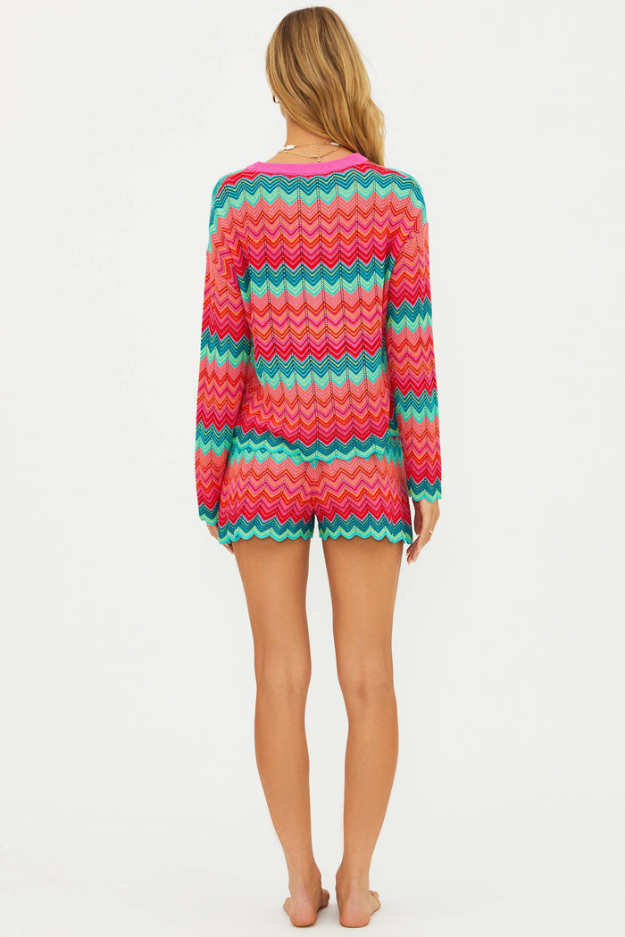 Person wearing a colorful striped sweater and shorts on a white background