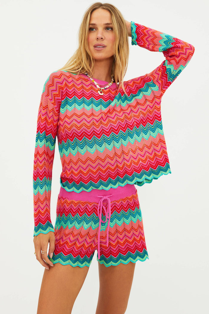 Woman wearing a colorful zigzag patterned outfit on a plain background