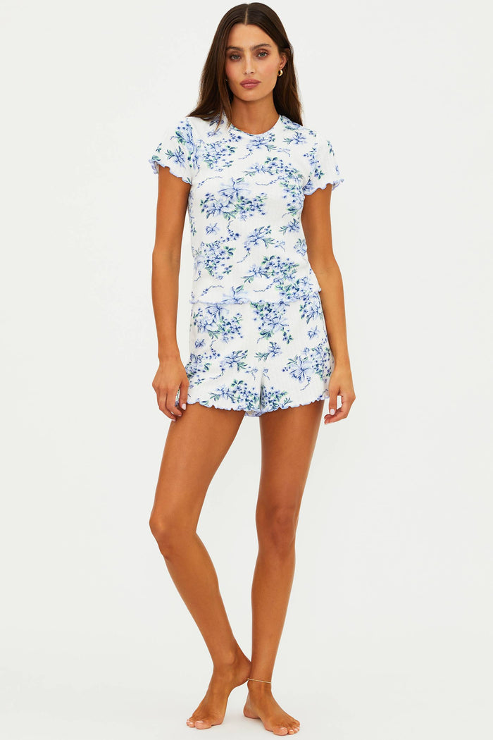 Woman wearing a white short sleeve and short set with blue floral pattern on a white background