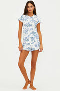 Woman wearing a white short sleeve and short set with blue floral pattern on a white background