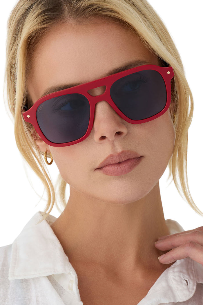 Woman wearing red sunglasses with a white shirt on a white background