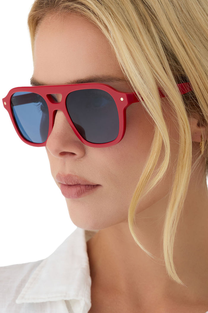 Woman wearing red sunglasses with a white shirt