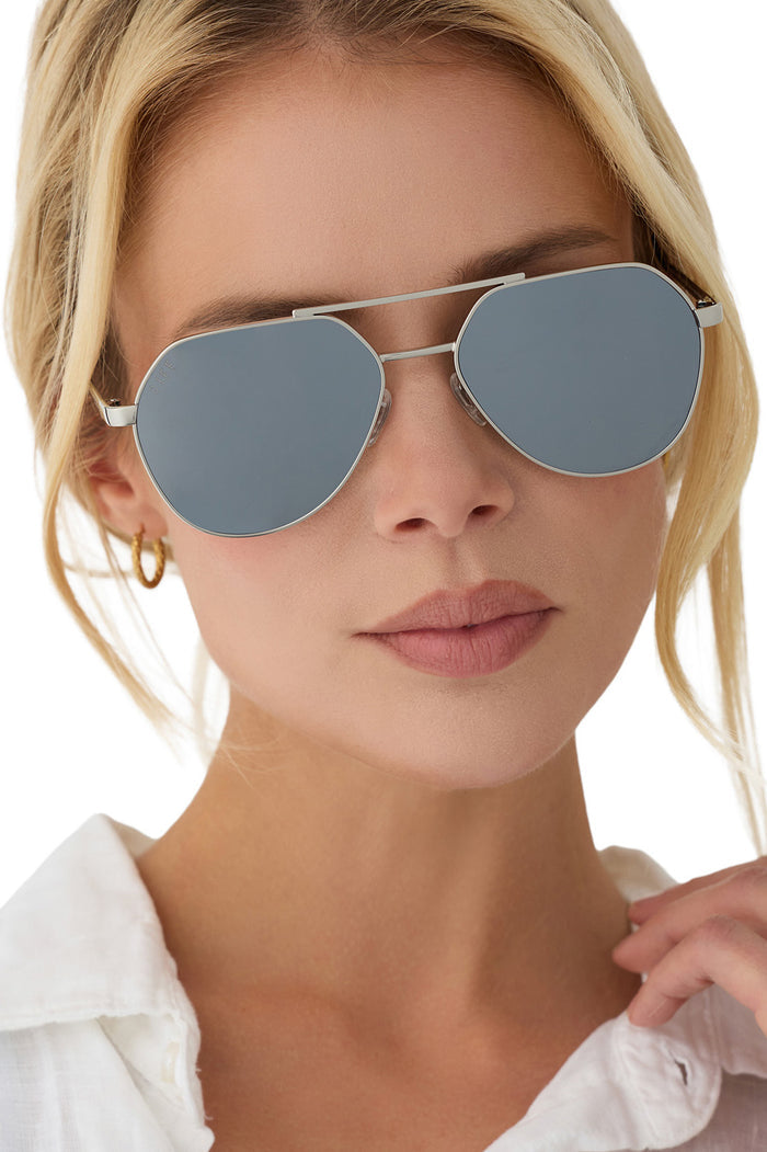 Person wearing silver-framed sunglasses with a blurred background