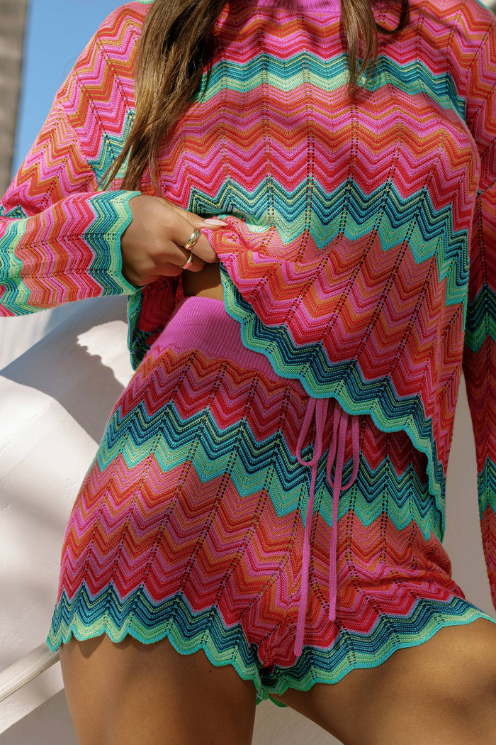 Person wearing a colorful chevron-patterned outfit with a hood.