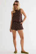 Woman wearing a brown polka dot sleeveless top and shorts on a white background