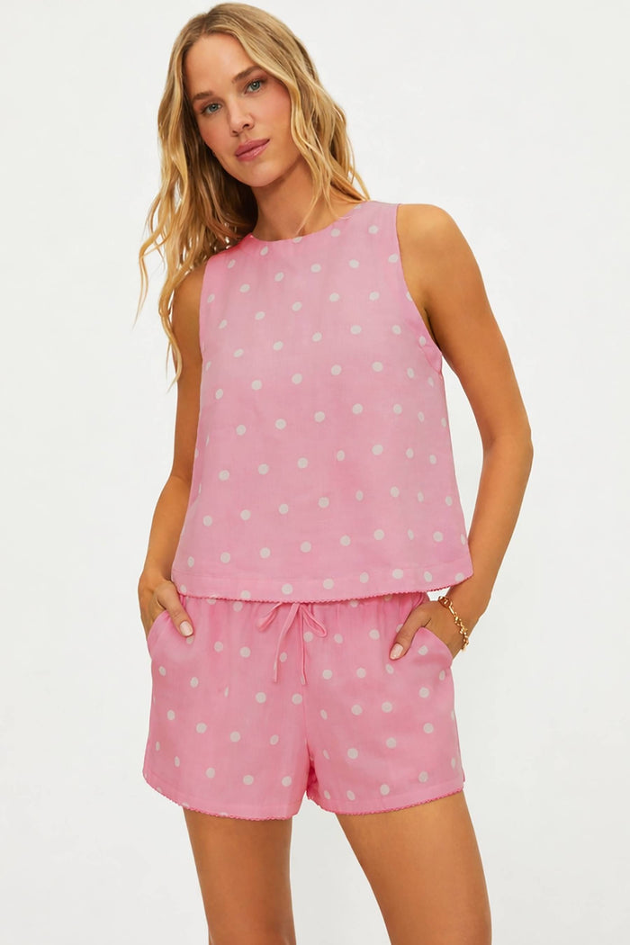 Woman wearing a pink polka dot sleeveless top and shorts set on a white background