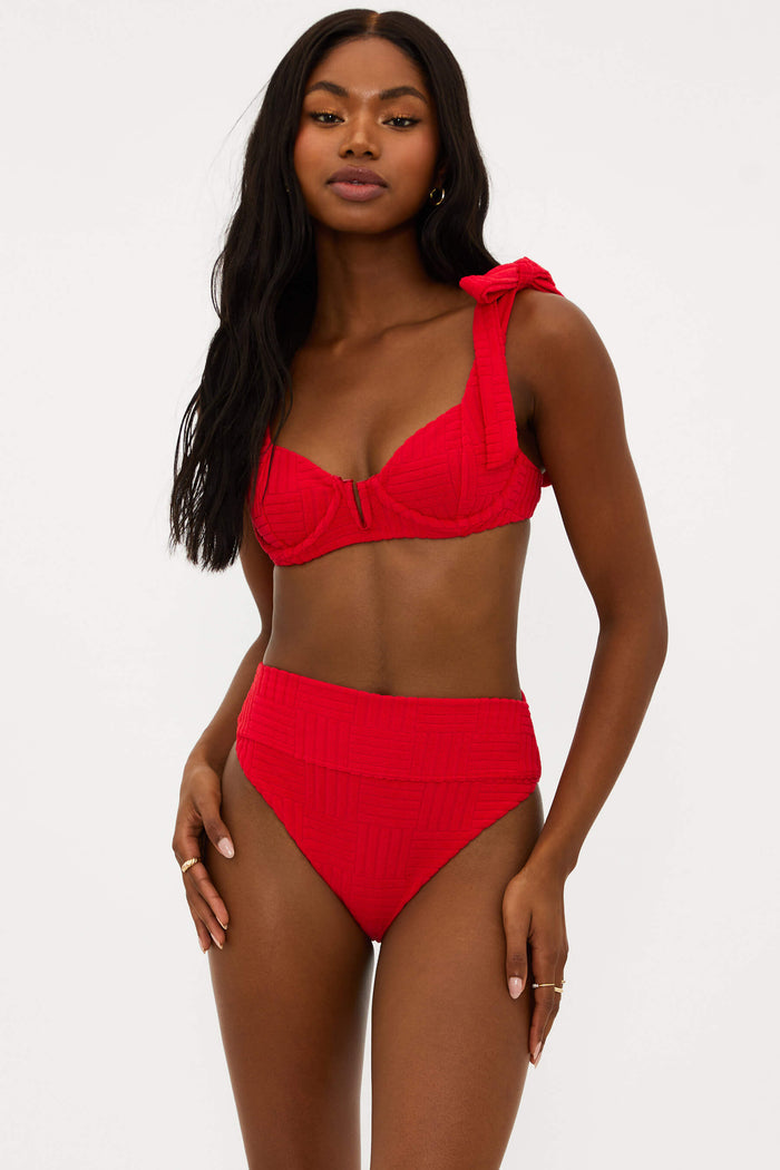 This image features the Blair Top Cherry Terry, a stylish and supportive swimwear top. Modelled by a woman showcasing a serious expression, the top is presented in a vivid cherry red color.