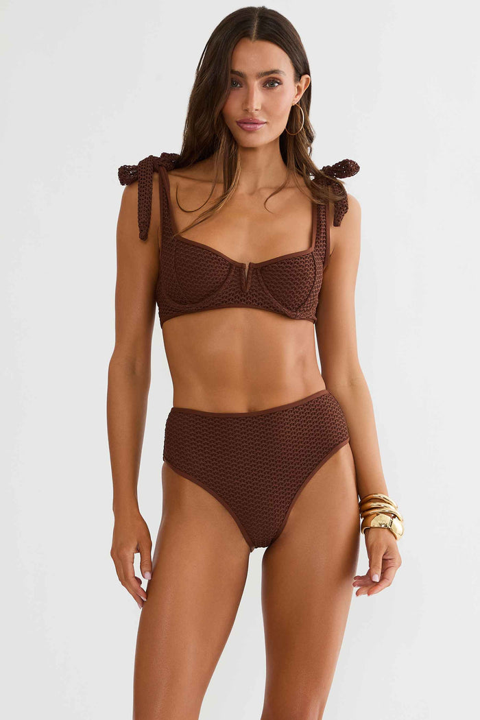 Woman wearing a brown bikini set with bow details on a white background