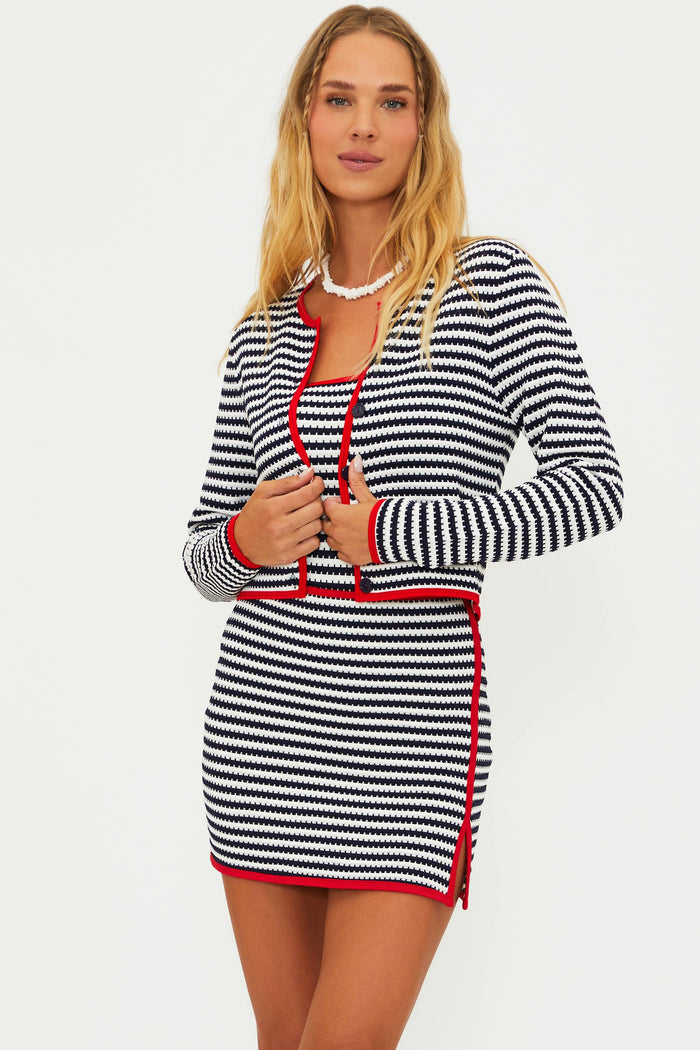 A female model wearing a striped cardigan with red contrast trim and a matching mini dress.