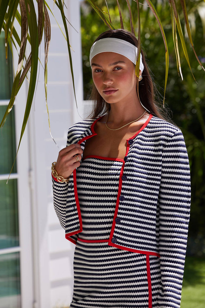 A female model wearing a striped cover-up with a cardigan-style top and red contrast trim.