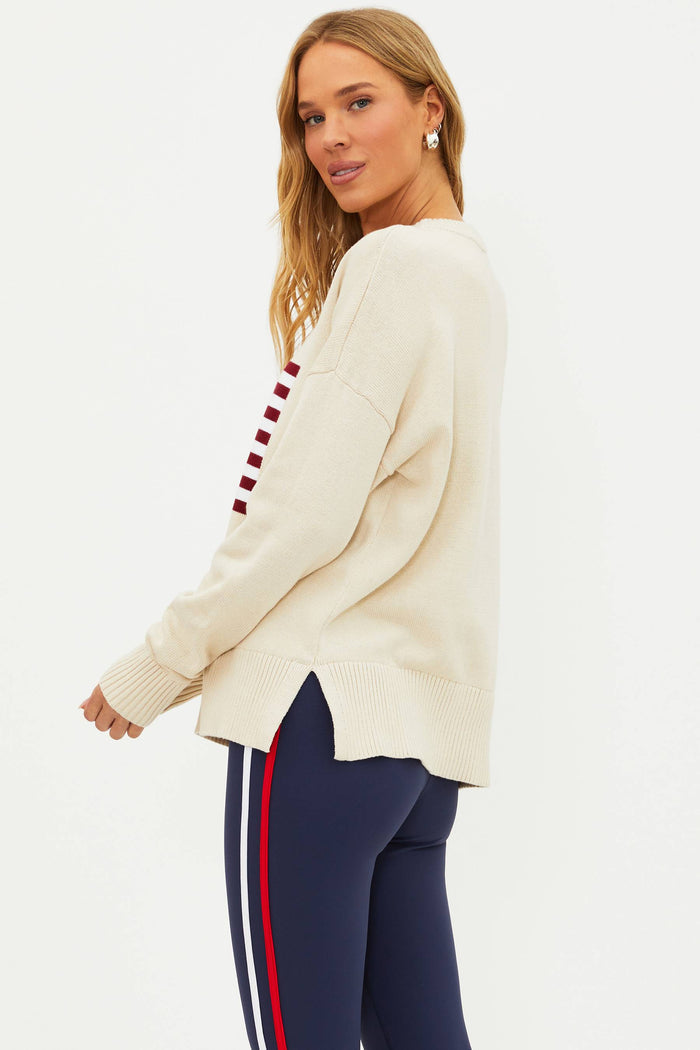 A female model wearing a white oversized crewneck sweater with a graphic of the American flag on the chest.