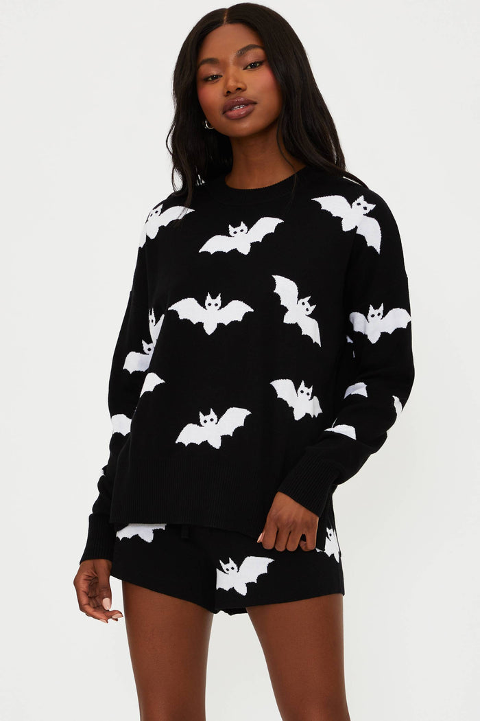 Woman wearing a black outfit with white bat patterns on a plain background