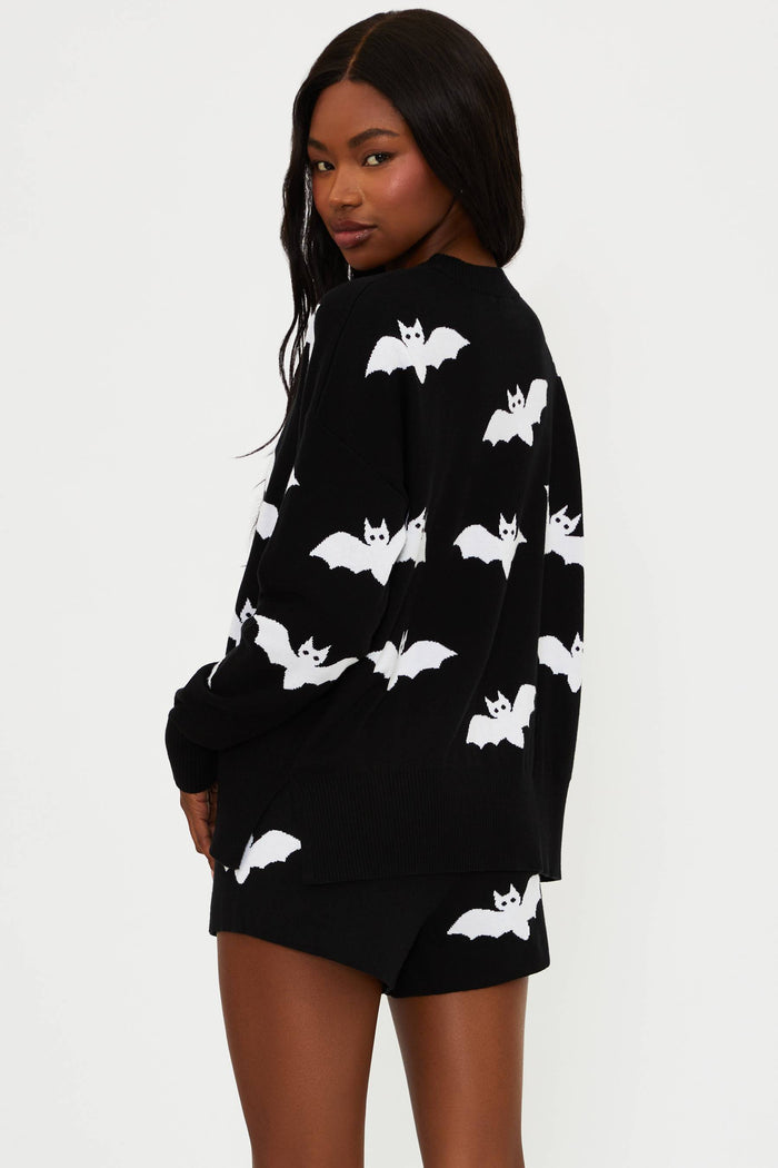 Black sweater with white bat patterns worn by a model on a white background