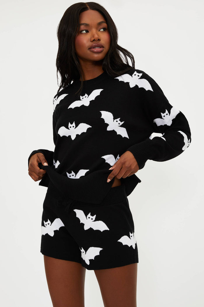 Woman wearing a black outfit with white bat patterns on a white background