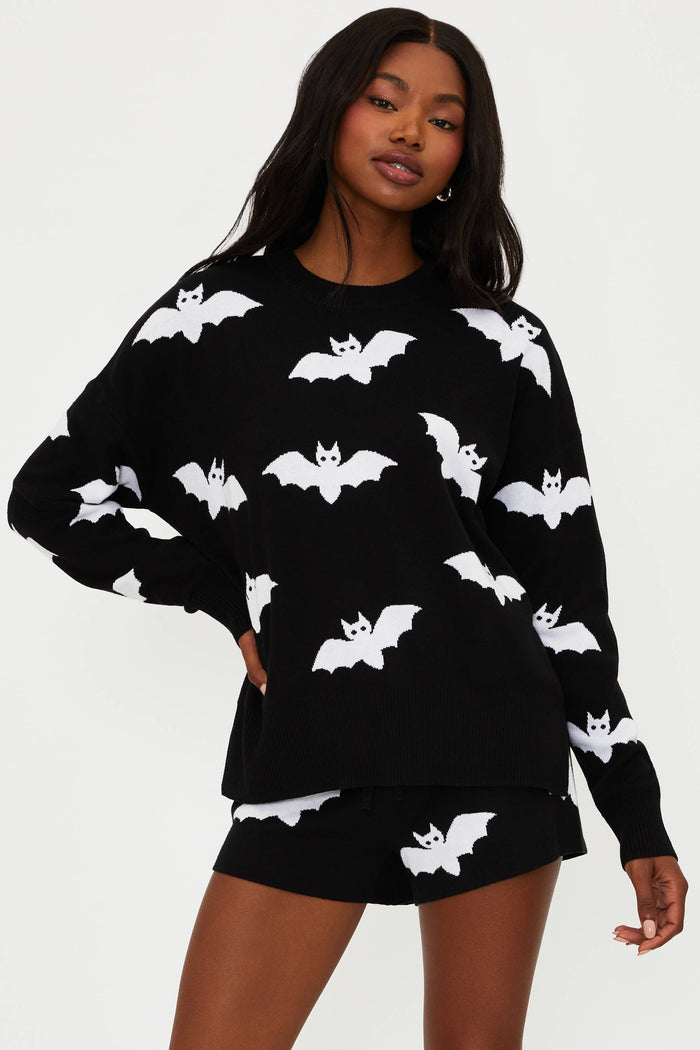 Person wearing a black sweater with white bat patterns on a plain background