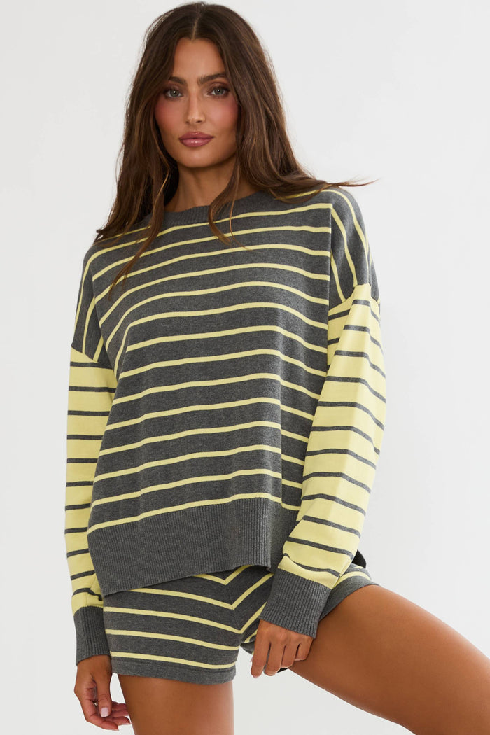 A woman modeling a striped knit sweater and matching shorts set. The set features horizontal stripes in dark gray and pale yellow, with solid dark gray sleeves and cuffs.