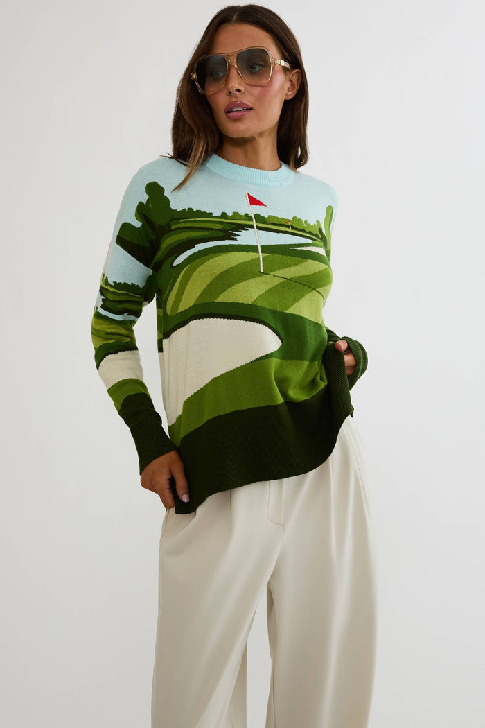 Woman wearing a sweater with a golf course design on a white background