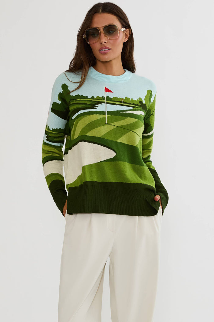 Woman wearing a sweater with a golf course design on a plain background