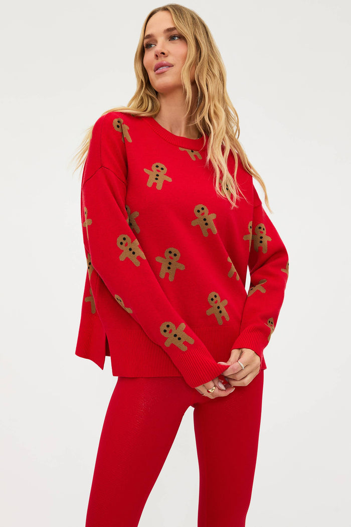Woman wearing a red sweater with gingerbread man patterns on a white background