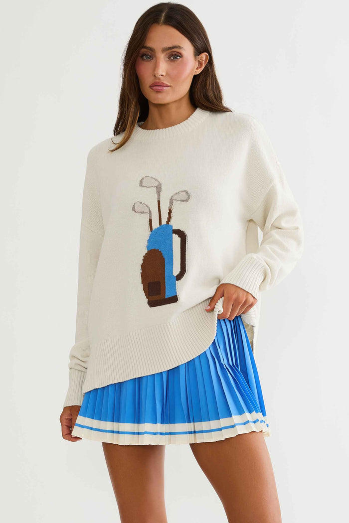 Woman wearing cream sweater with golf clubs on it.