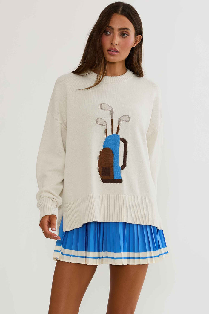 Woman wearing cream sweater with golf clubs on it.