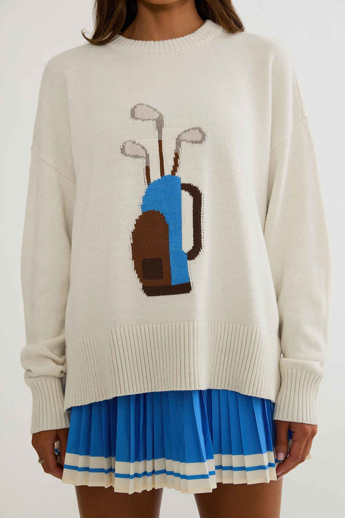 Woman wearing cream sweater with golf clubs on it.